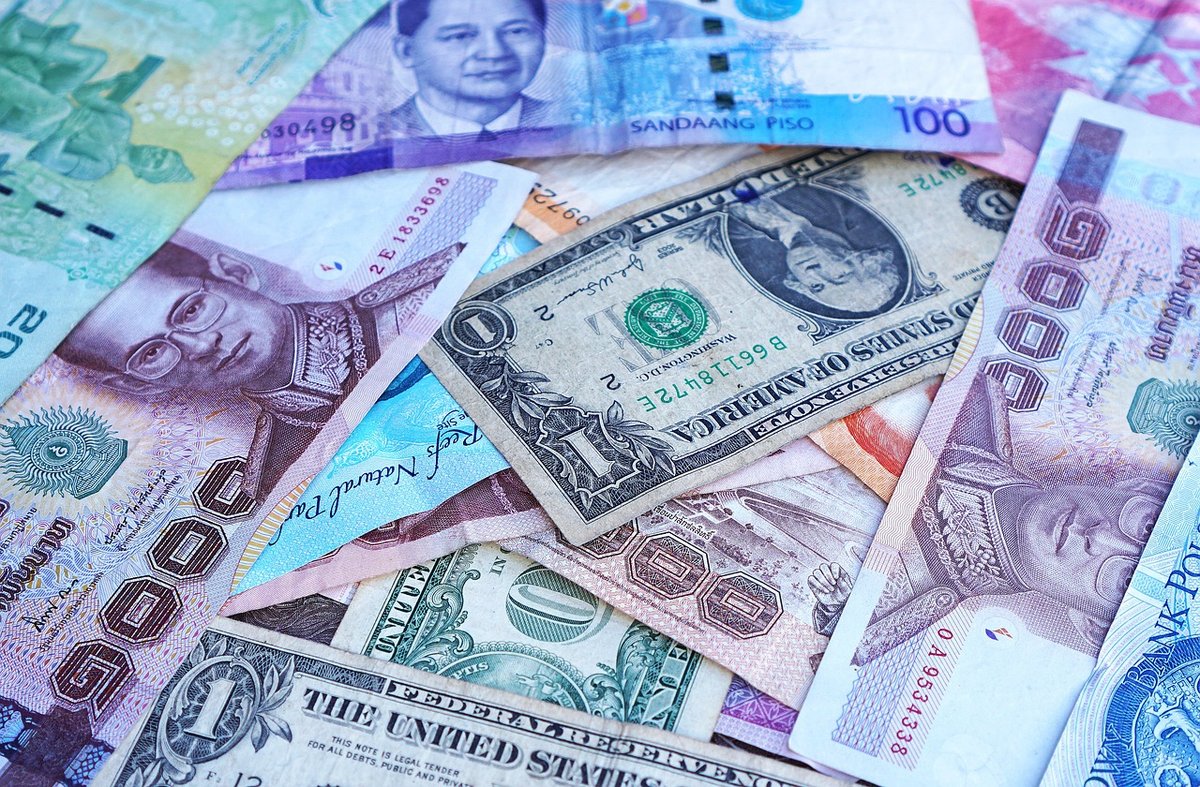 Various international banknotes, including Thai baht and US dollars, representing tax considerations for digital nomads in Thailand