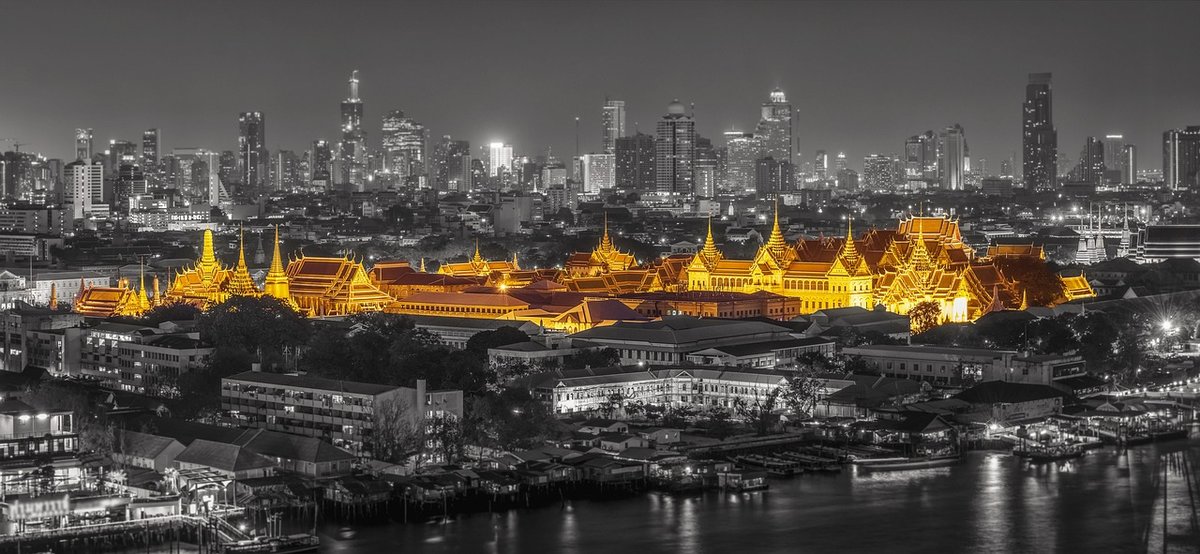 "Night view of Bangkok city skyline with the Grand Palace illuminated in gold, representing the prestige of the Golden Visa Thailand program"