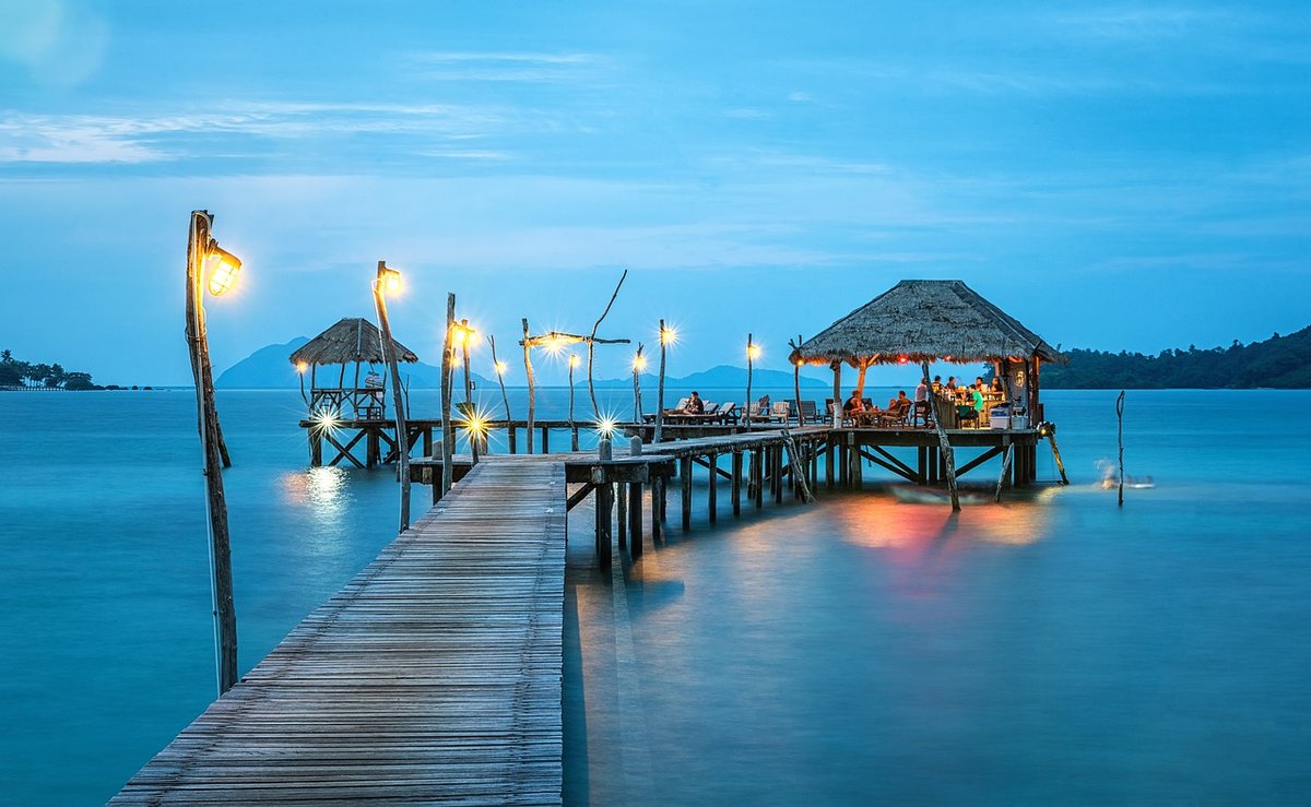 "Scenic overwater restaurant on a wooden pier at sunset, symbolizing the relaxed lifestyle available with a Thailand retirement visa for US citizens"