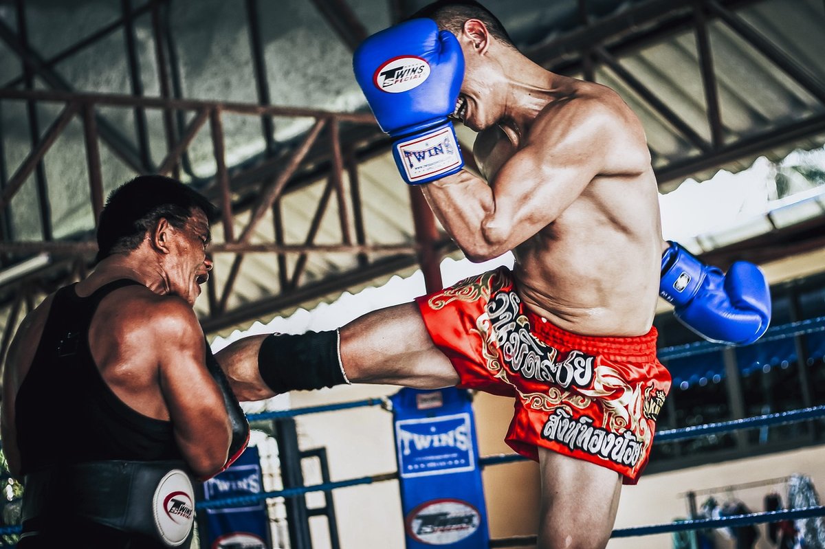 Muay Thai fighter in red shorts delivering a powerful kick during training in Thailand, representing the Muay Thai visa program for international students